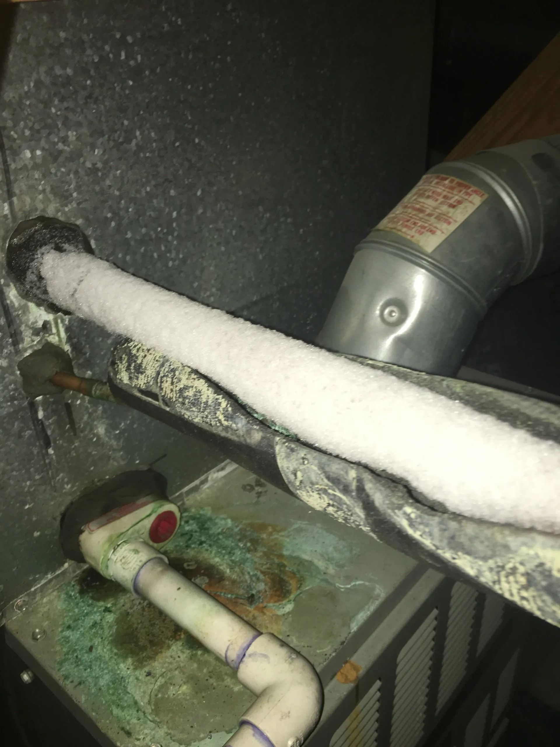 Frost covering a pipe connected to an HVAC unit; condensation evident.