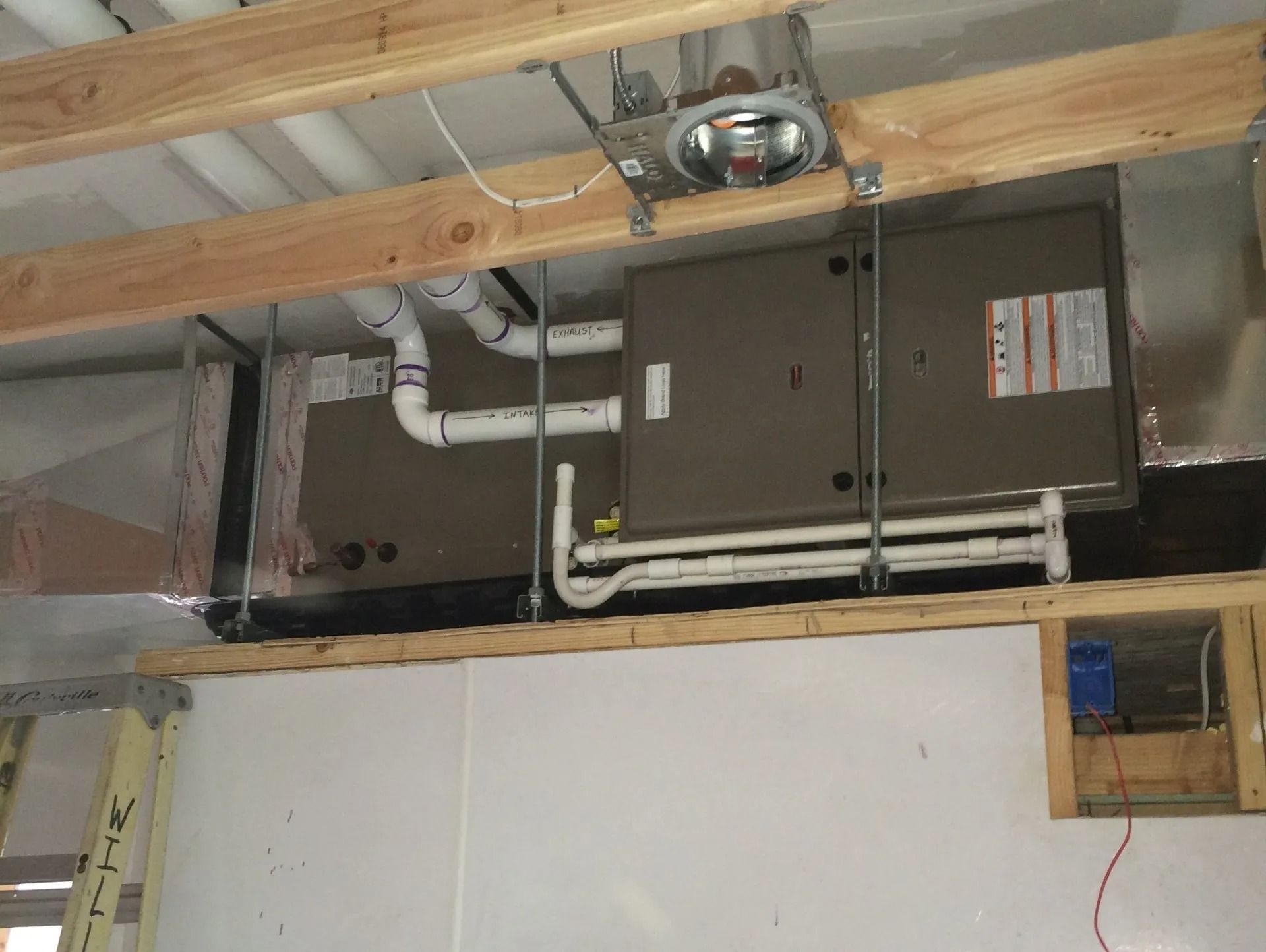 Furnace and air handler system in a basement with ductwork, supported by wooden beams.
