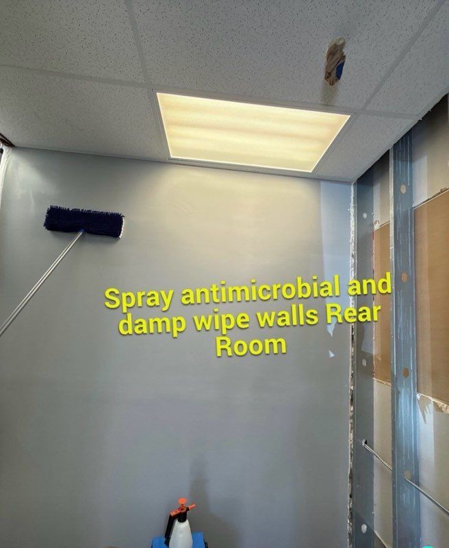 Interior view of a room with instructions to spray walls with antimicrobial and damp wipe.