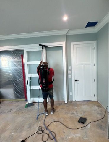 Person using a backpack vacuum to clean a doorway during construction.