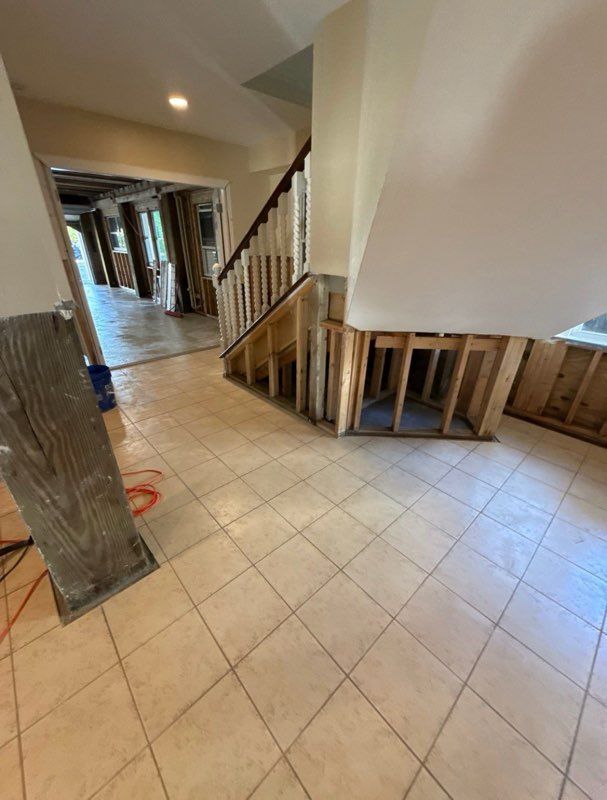Interior undergoing renovation: exposed framing near staircase, tile floors, hallway visible.