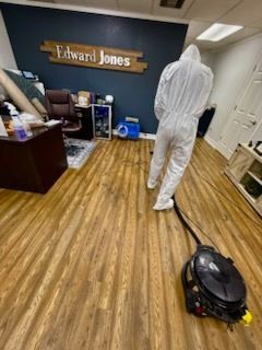 Person in protective suit cleaning an Edward Jones office floor with a machine.