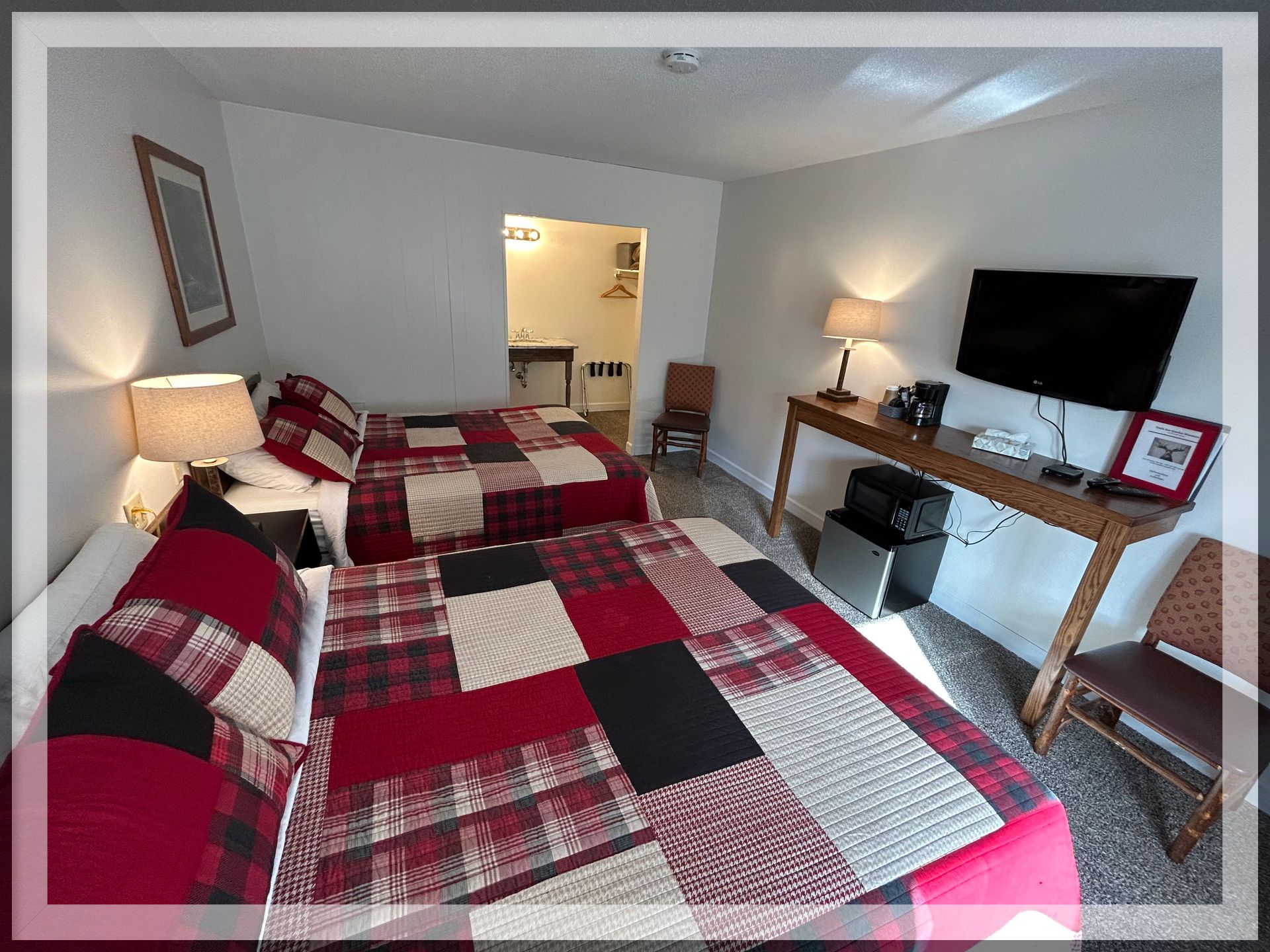 This is an image of a bedroom with wall-mounted TV, and main table in a remodeled Double Queen Room.