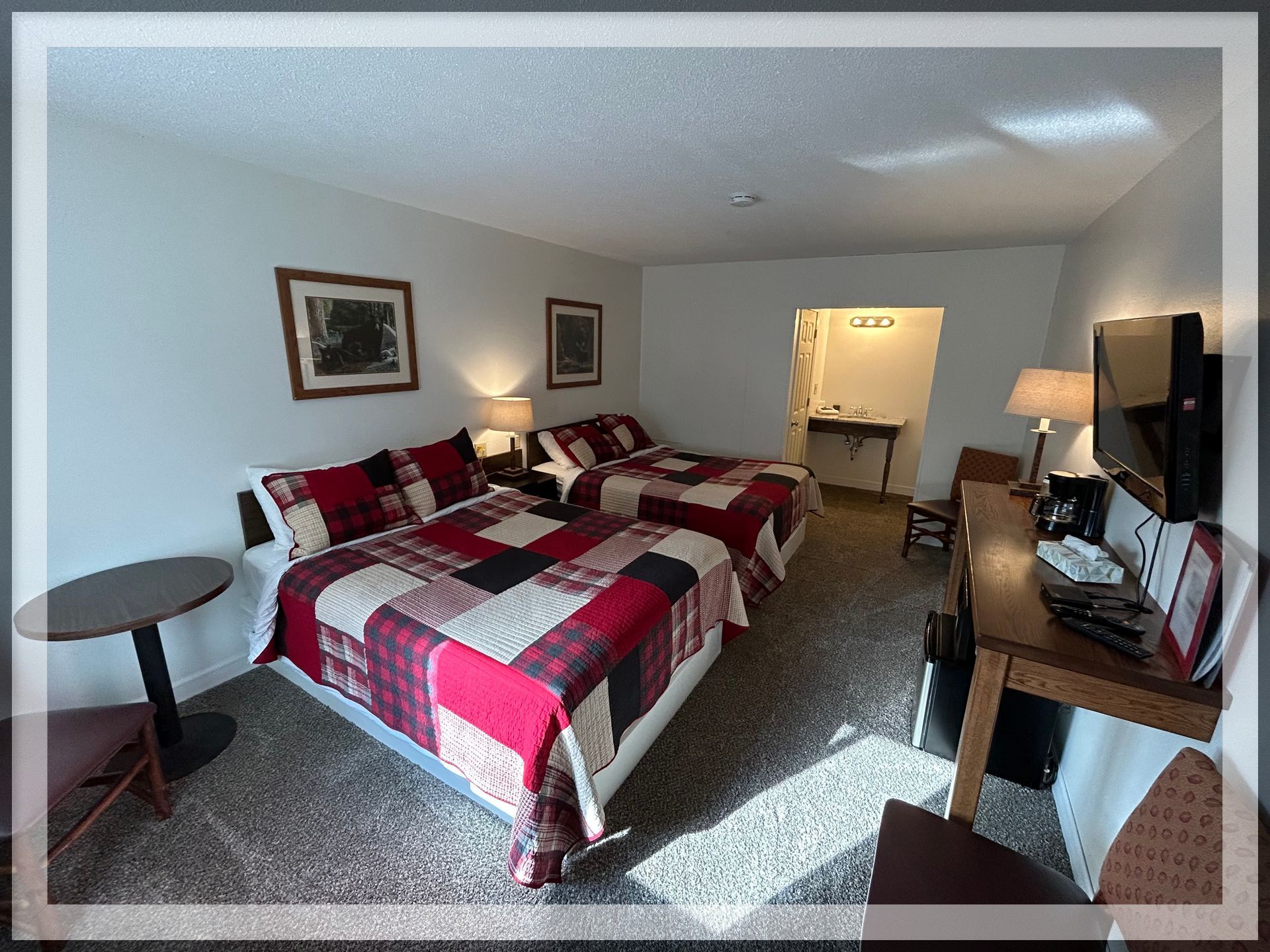 This is an image of the bedroom with the main bathroom entrance in a remodeled Double Queen Room.