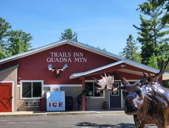 An image of the front office of The Trails Inn Quadna Mountain Motel with a moose statue.