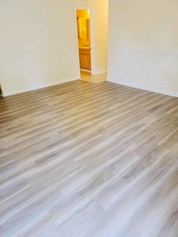 Black tool bag on grass, filled with tools like a level, scissors, tape measure, and headphones.