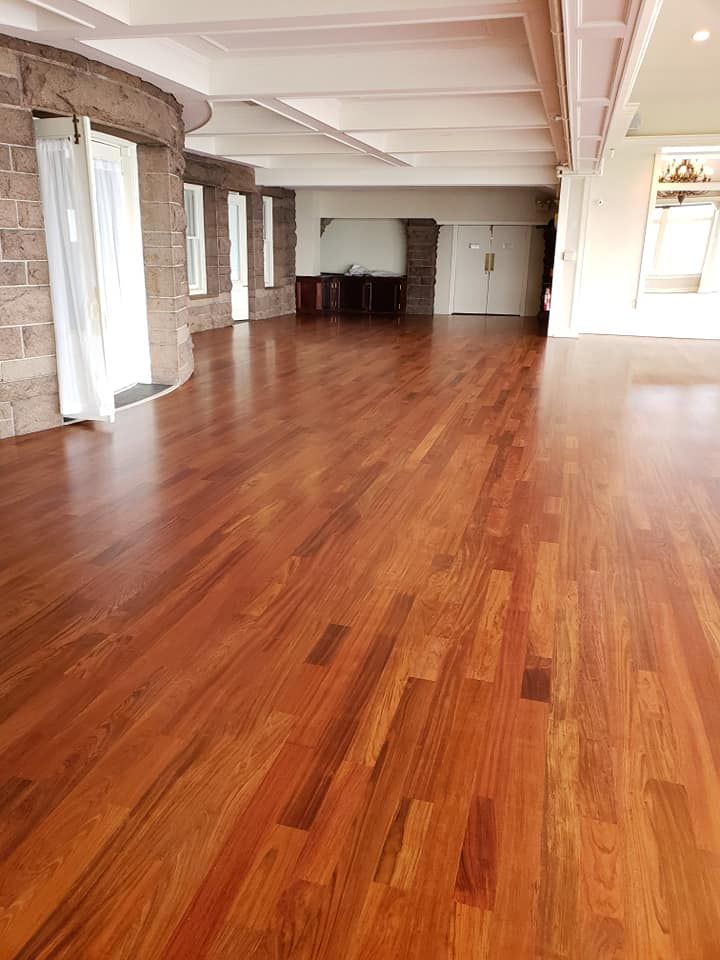 Black tool bag on grass, filled with tools like a level, scissors, tape measure, and headphones.
