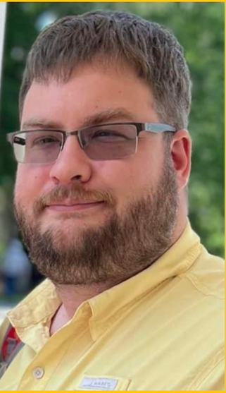 a man with a beard and glasses is wearing a yellow shirt .