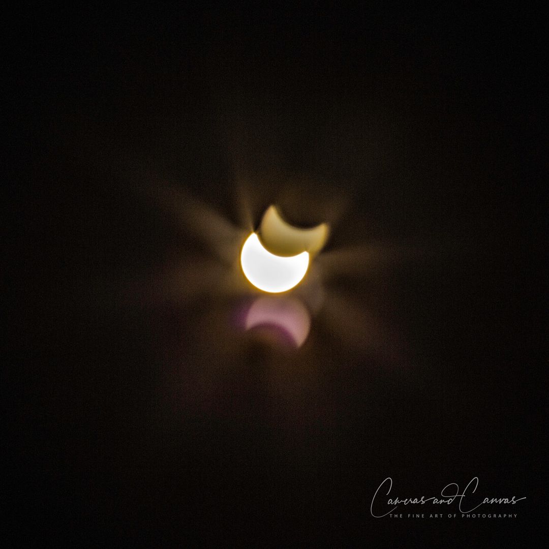 Solar eclipse with crescent shapes, bright light, and dark background.