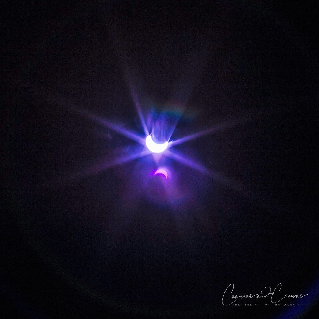 Partial solar eclipse with bright starburst effect in dark sky.