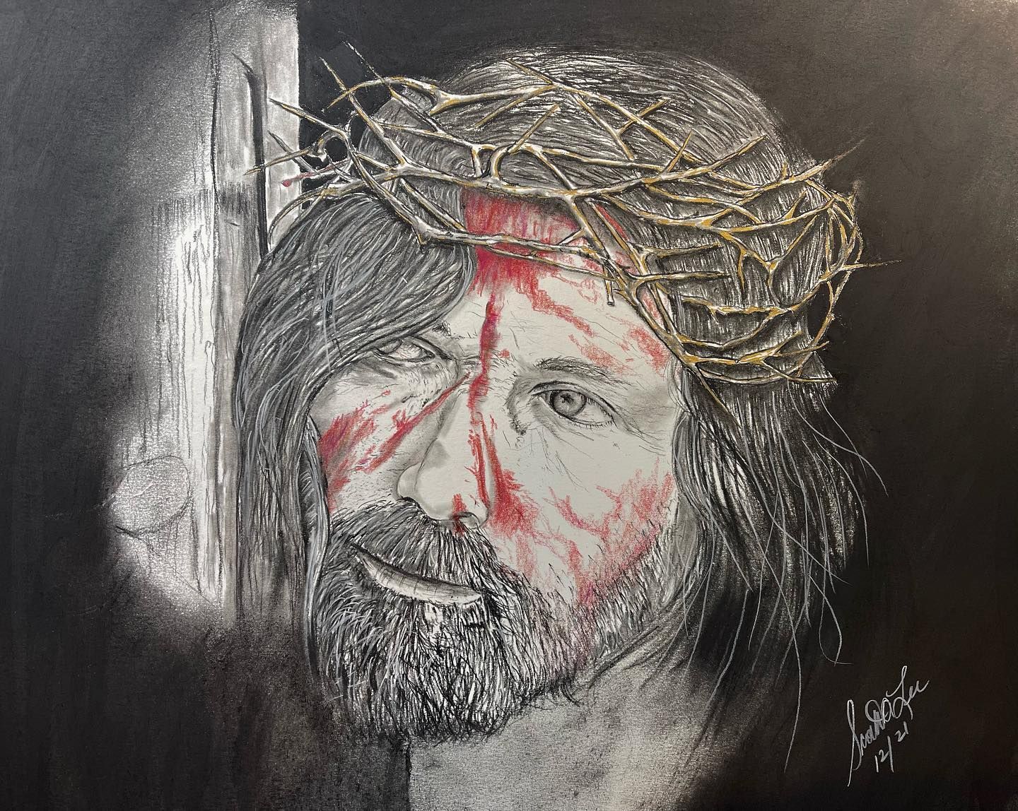 Jesus wearing a crown of thorns, with blood on his face, looking toward the viewer against a black background.