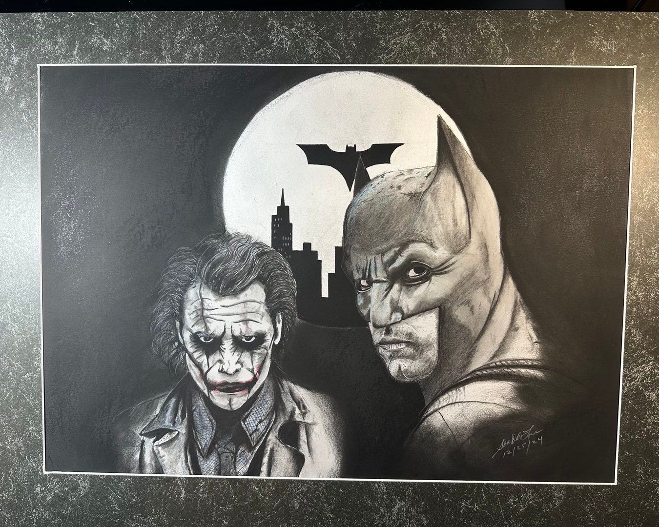 Batman and the Joker in grayscale, with a bat silhouette over a city against a full moon.