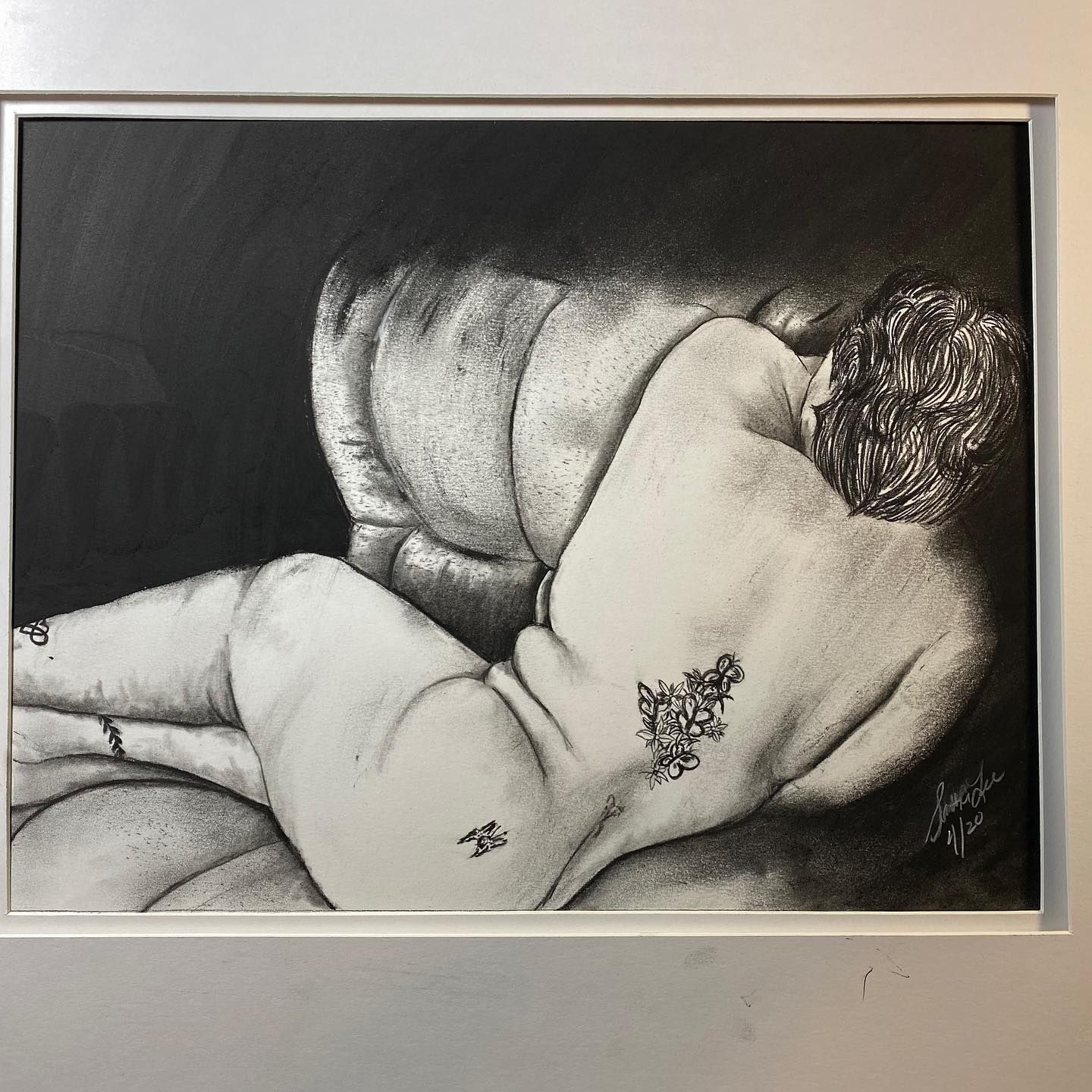 Black and white drawing of a person reclining on a couch, back towards viewer; small tattoos on the body.