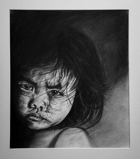 Charcoal drawing of a child with a serious expression, dark hair, and speckled skin.