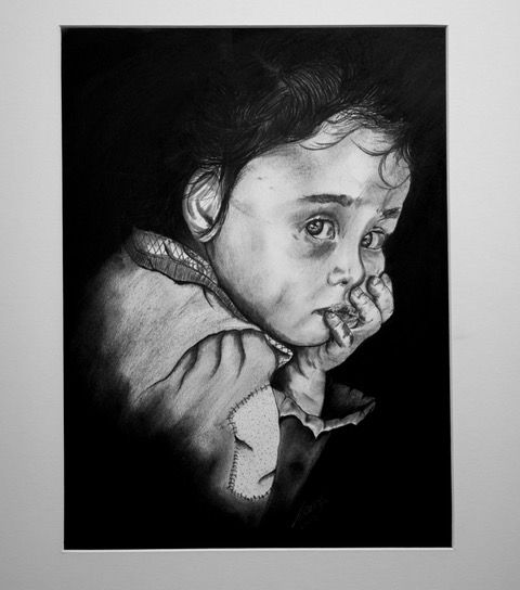 Charcoal portrait of a child with a sad expression, resting chin on hand against a black background.