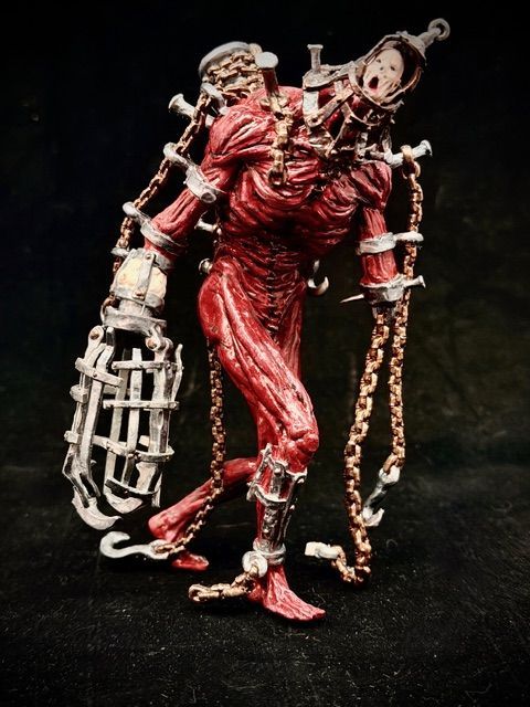 A horrifying red-skinned figure with chains, cages, and a lantern.