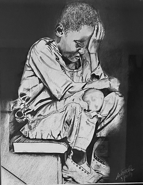 A child sits hunched over, head in hand, in shadow, wearing long sleeves and shoes.