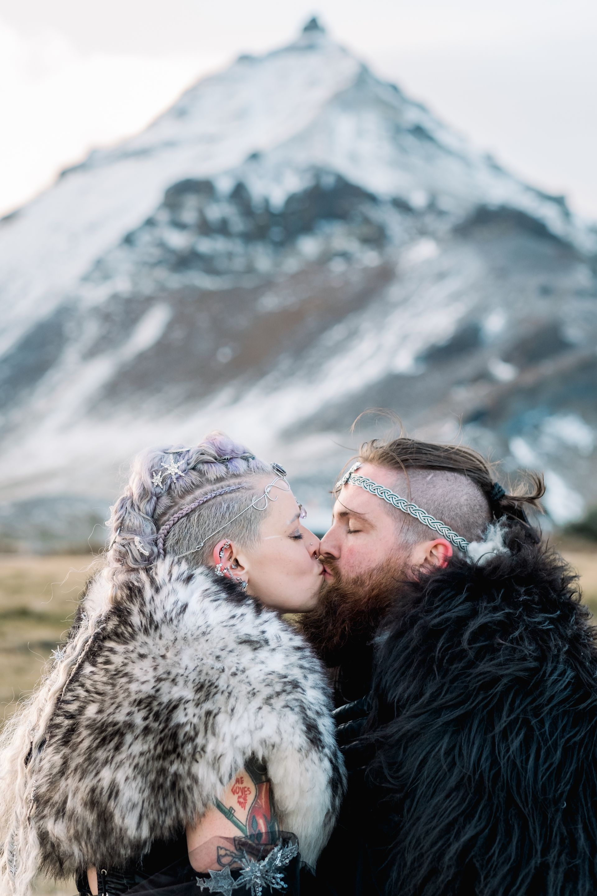 A man and a woman are kissing in front of a mountain.