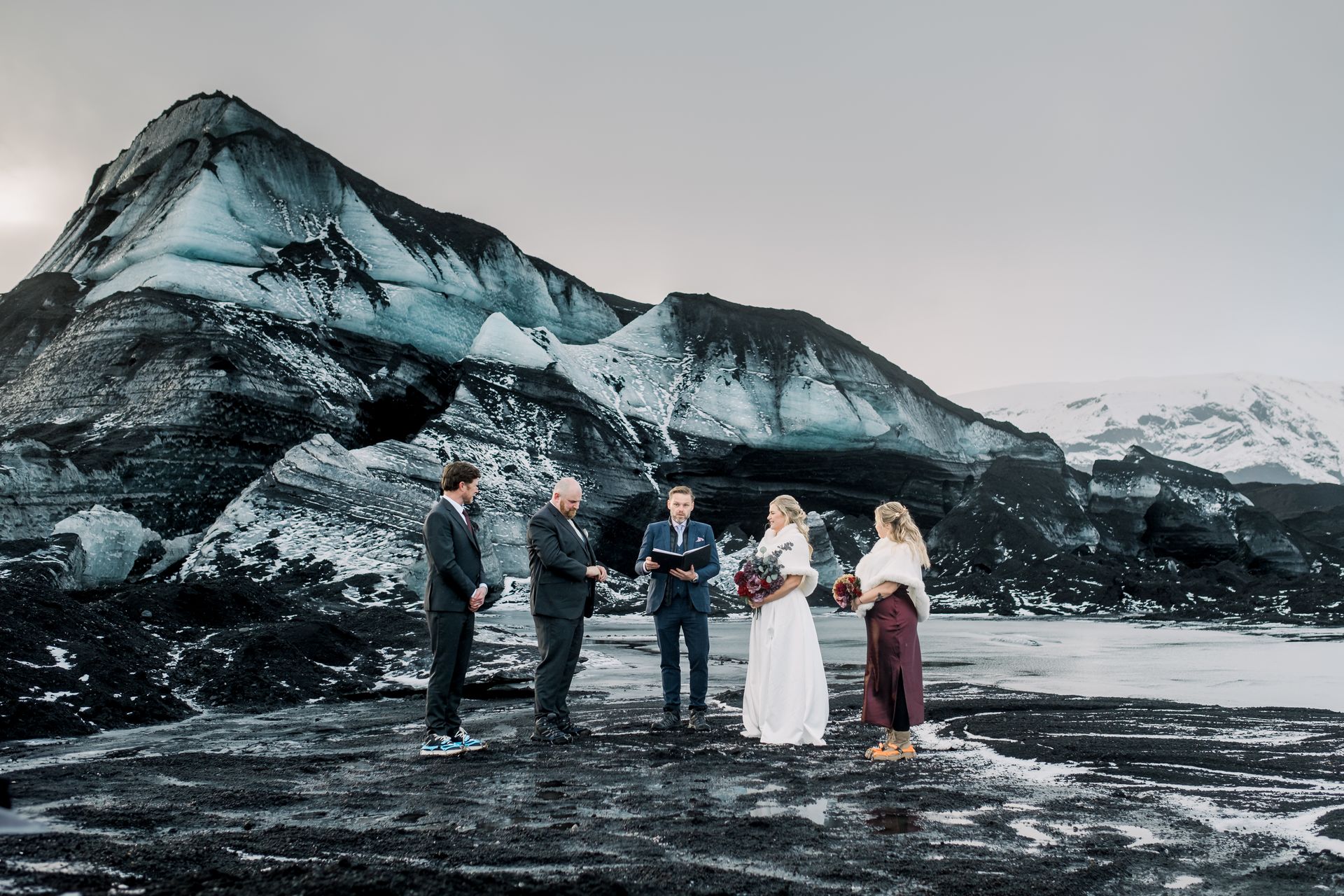 A couple celebrates their elopement with their witnesses at the stunning Katla Ice Cave.