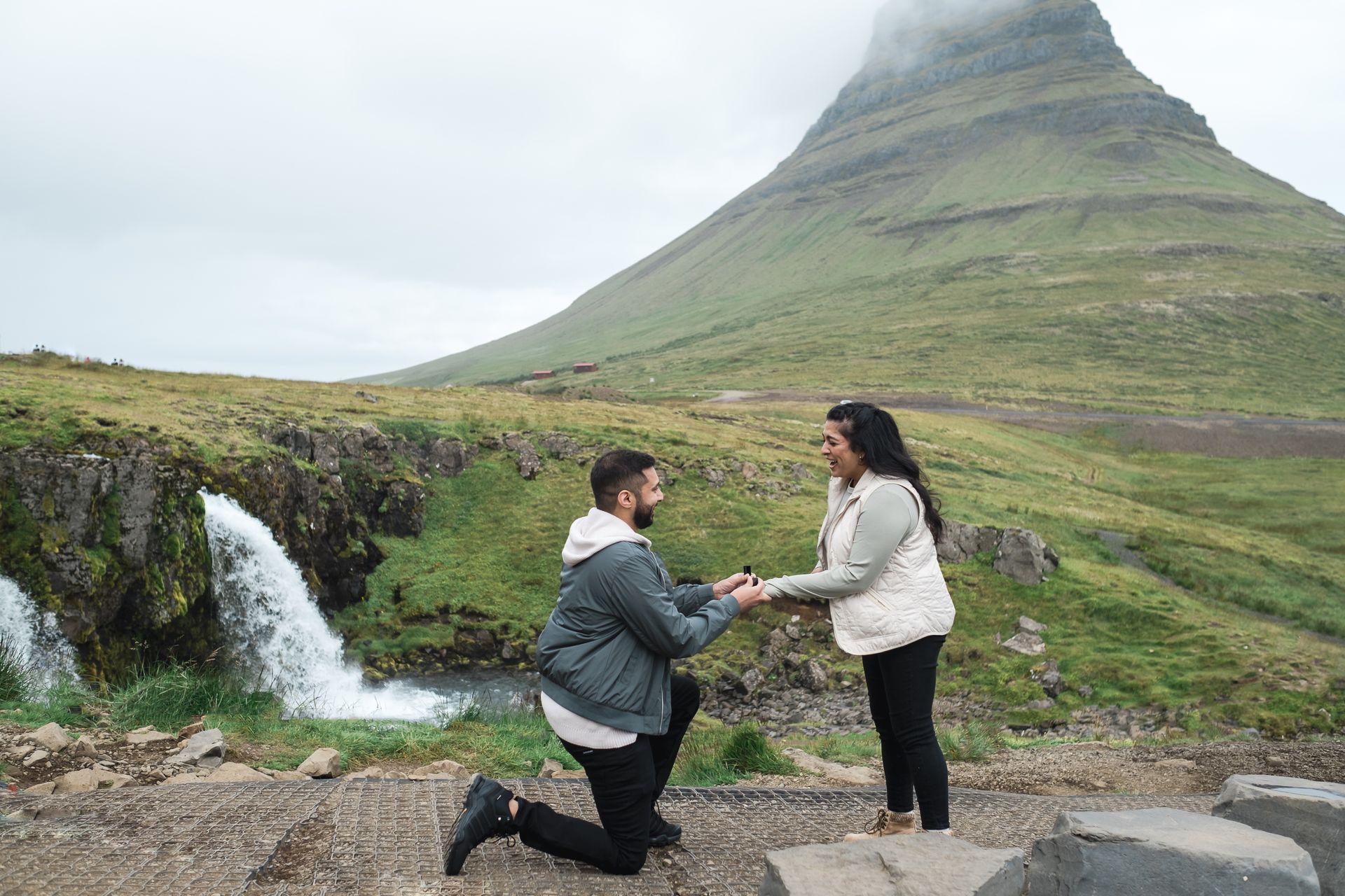 A man proposing on his knees to his girlfriend in front of Mount Kirkjufell in Iceland