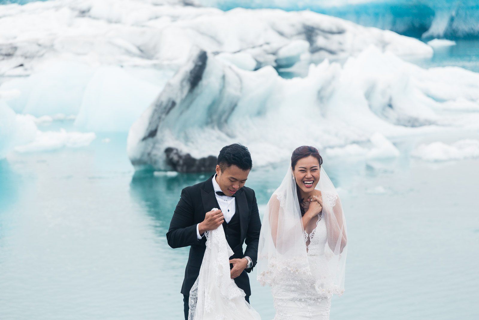 Married couple is laughing in front of Jökulsárlón Glacier Lagoon in Iceland. Iceland elopement and wedding photographer