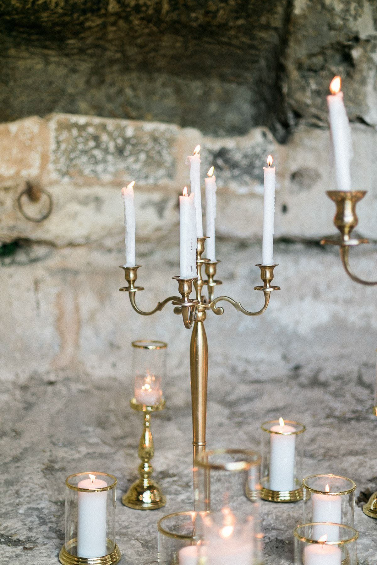 A bunch of candles are lit in candle holders on a table.