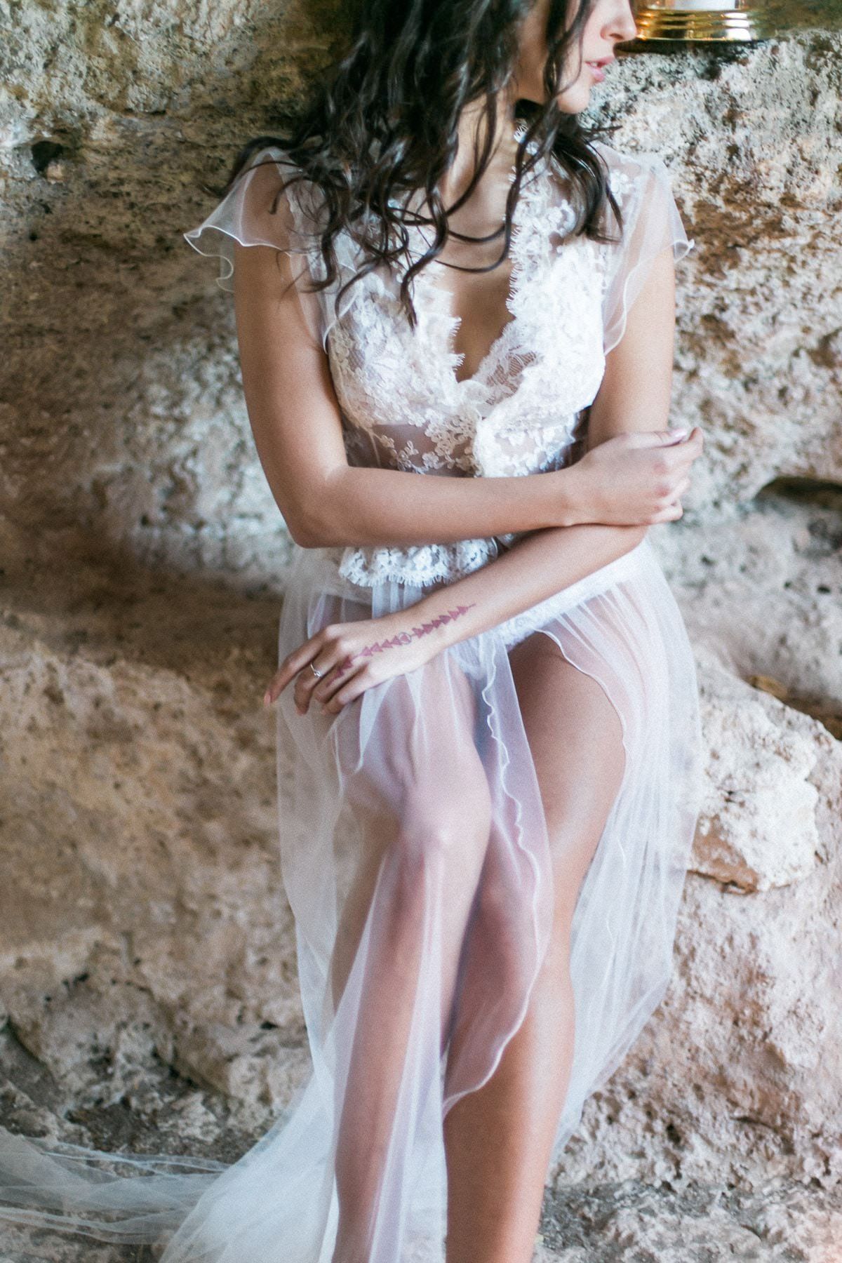 A woman in a white dress is sitting on a rock.