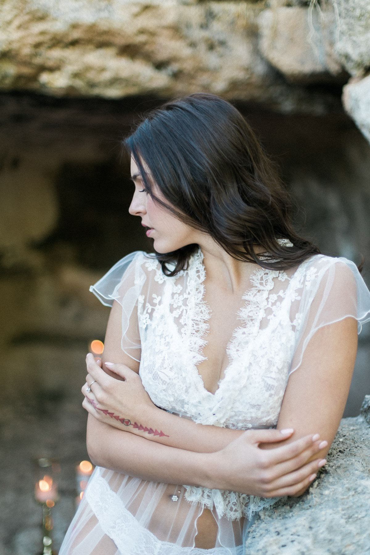 A woman in a white dress is standing next to a rock.