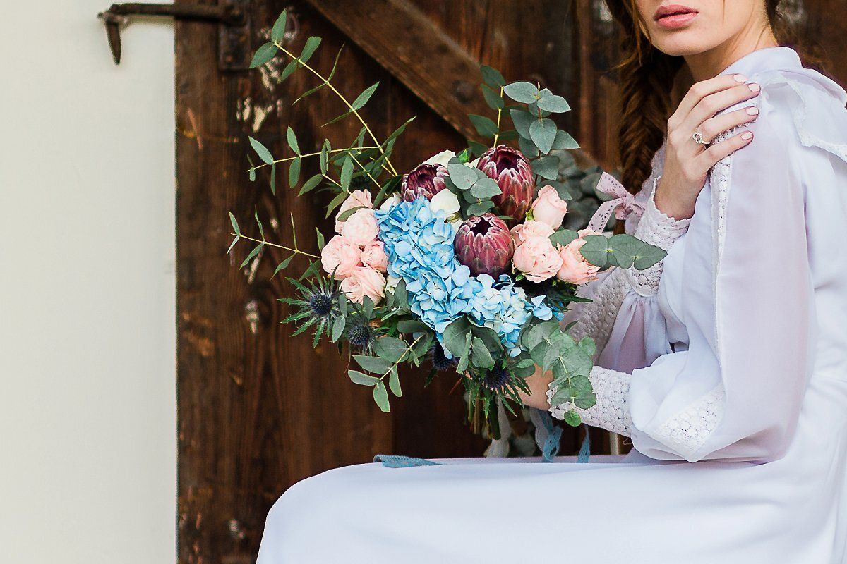 A woman in a white dress is holding a bouquet of flowers.