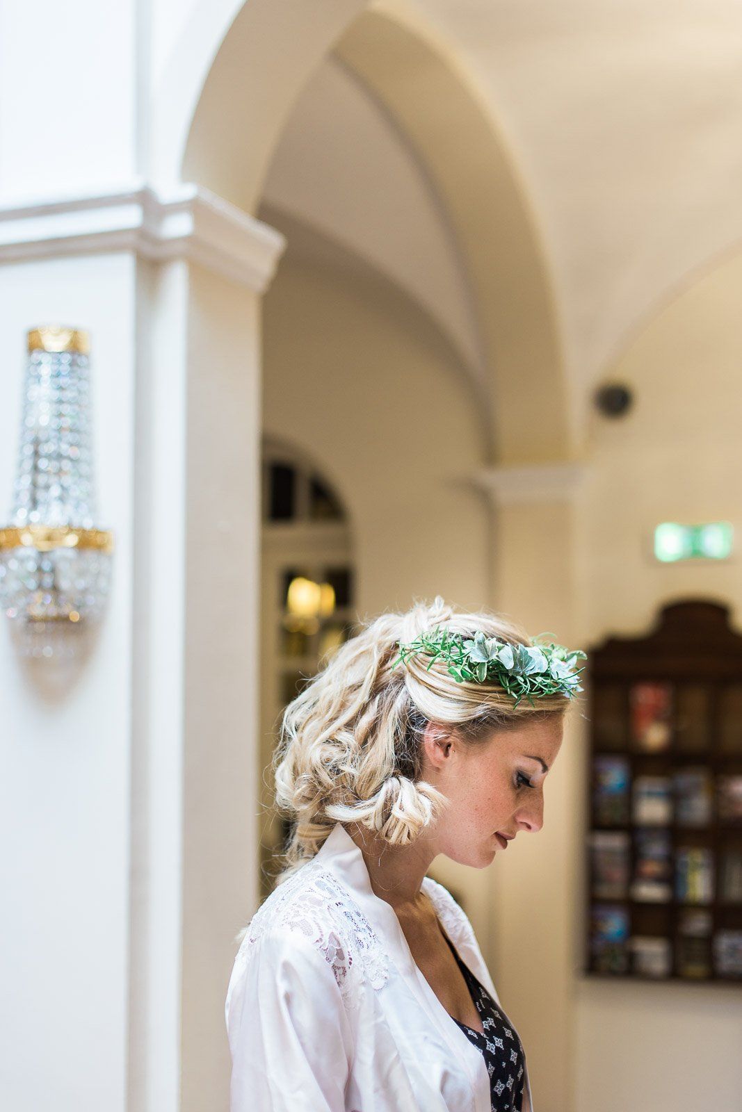 A woman wearing a flower crown is standing in a hallway.