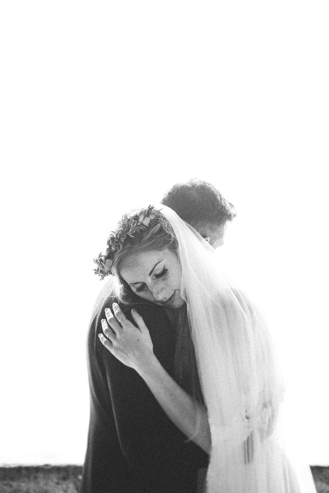A black and white photo of a bride and groom hugging each other.