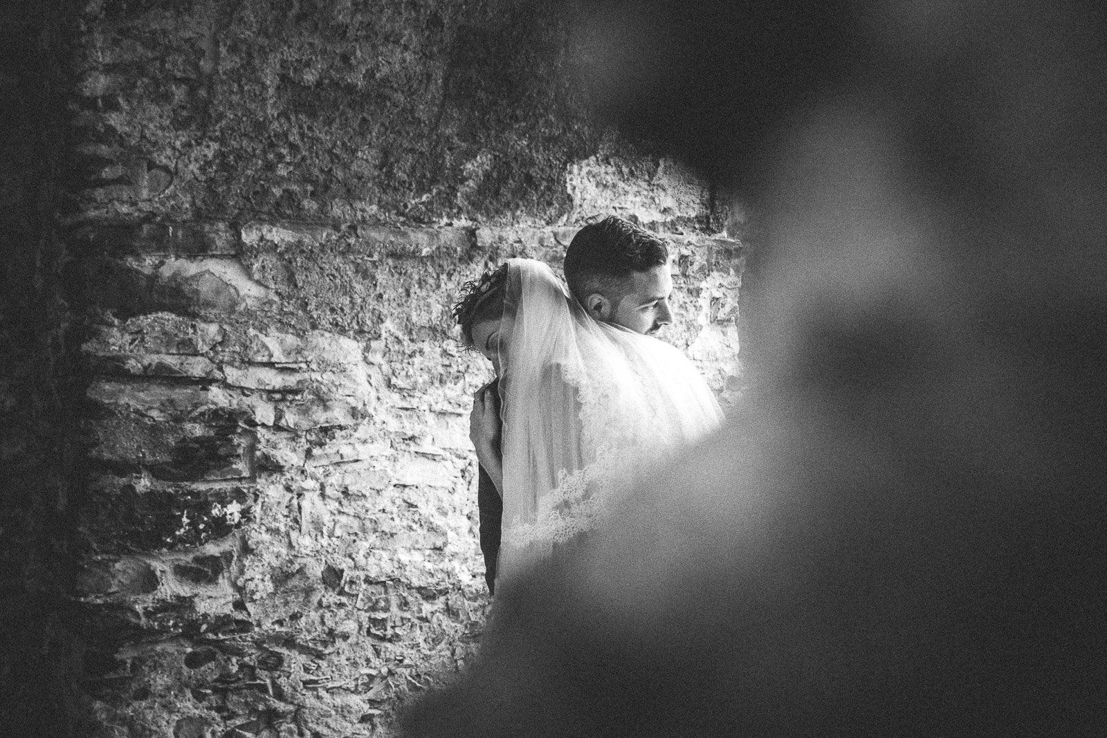 A black and white photo of a bride and groom hugging each other.