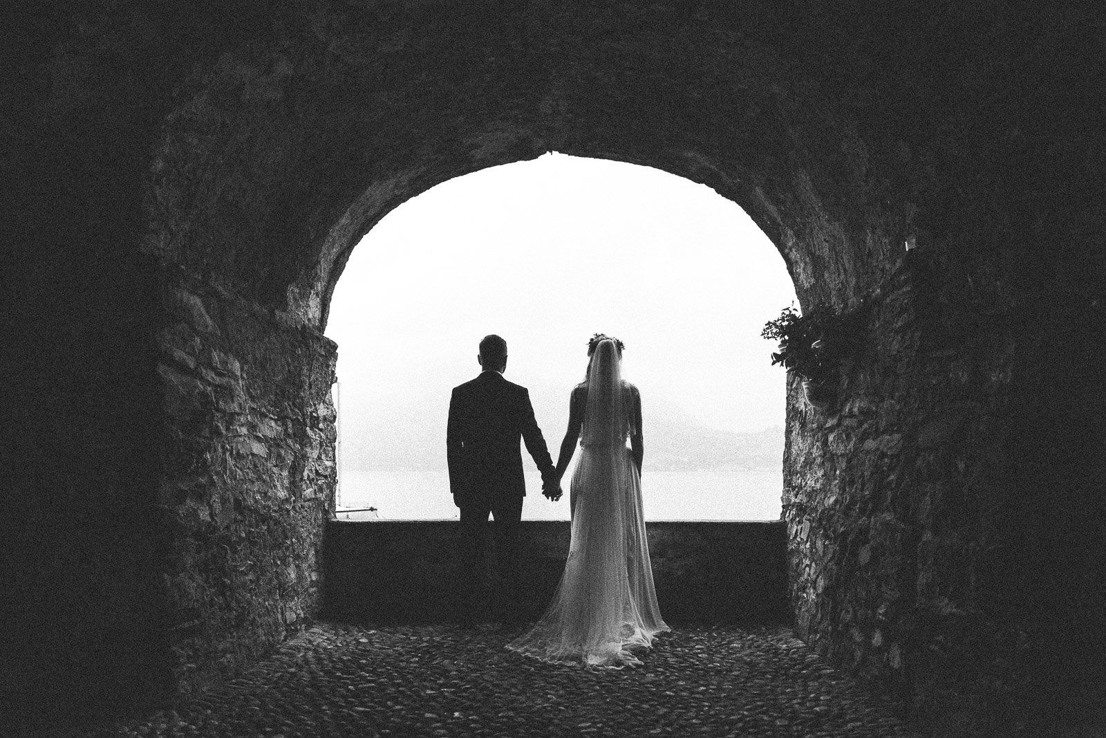 A black and white photo of a bride and groom holding hands