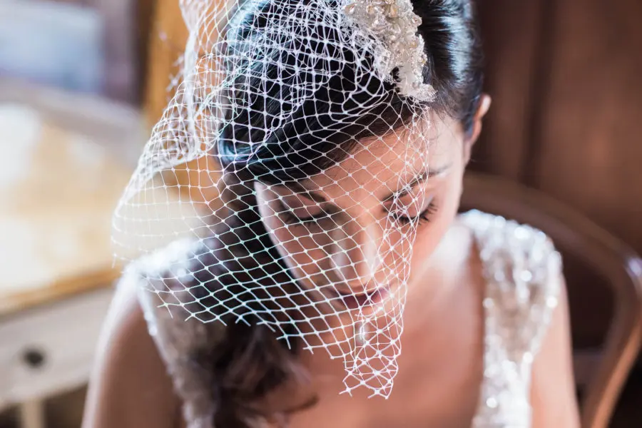 A woman in a wedding dress and veil is sitting in a chair.