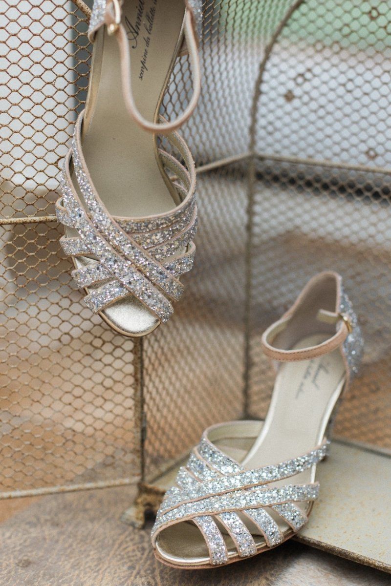 A pair of wedding shoes are sitting on a table next to a mirror.