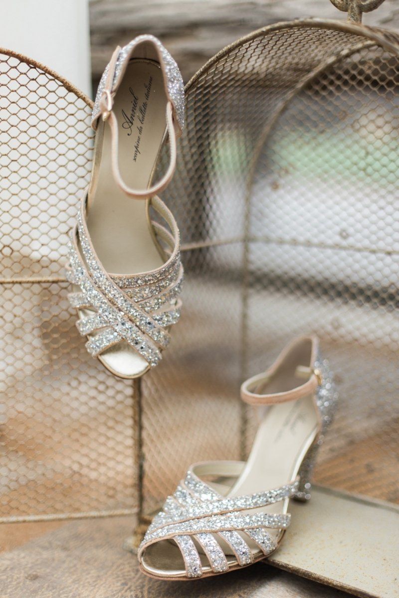 A pair of wedding shoes sitting on top of a mirror.