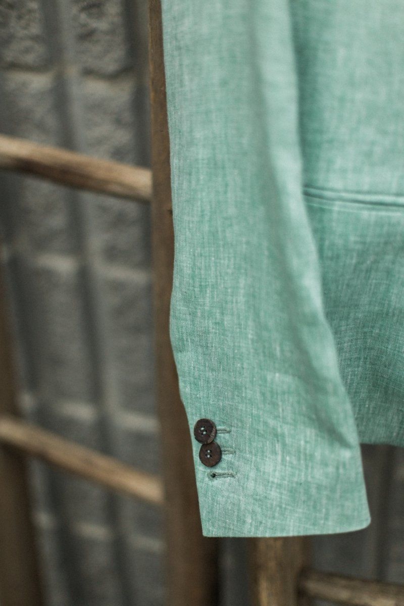 A green jacket is hanging on a wooden ladder.