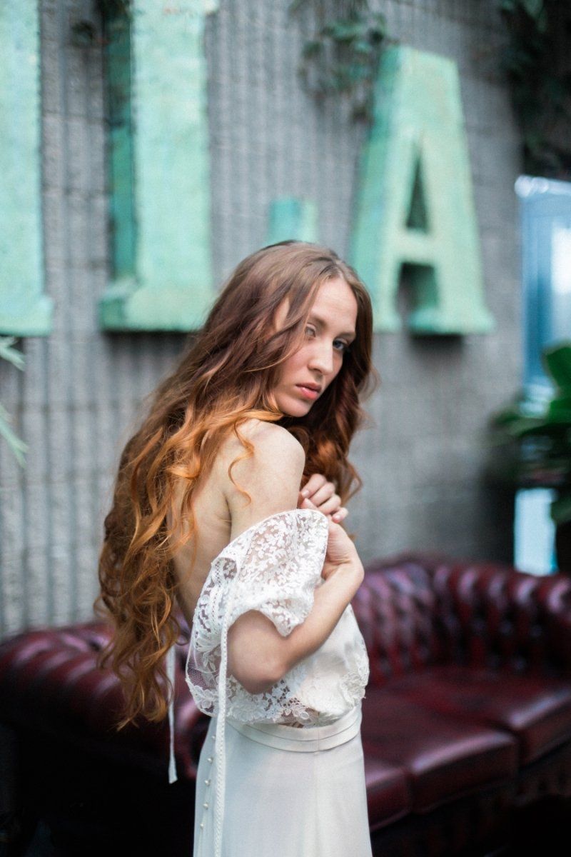 A woman in a white dress is standing next to a red couch.
