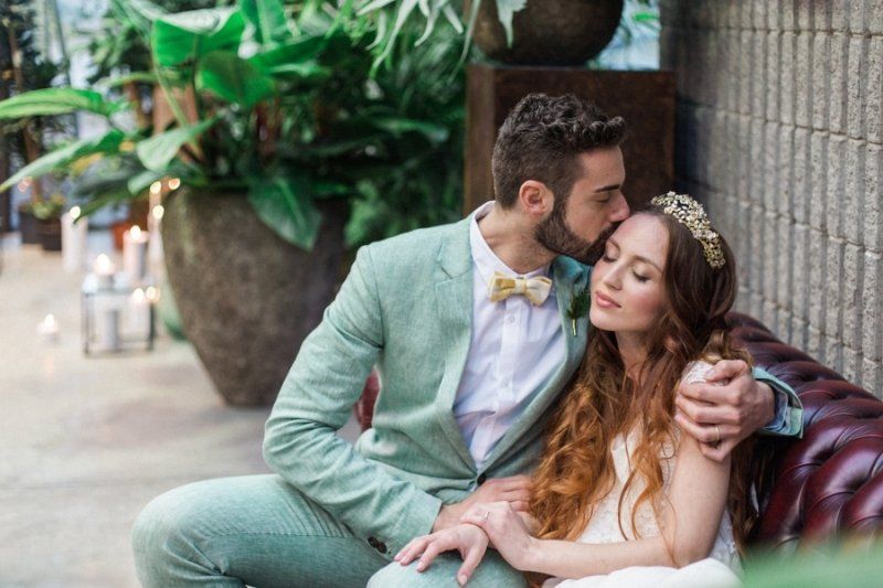 A bride and groom are sitting on a couch and kissing.
