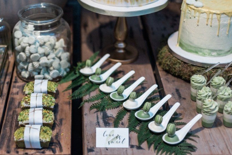 A wooden table topped with a variety of desserts and spoons.