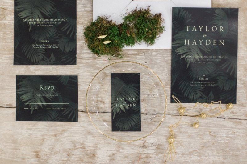 A set of wedding invitations and rsvp cards on a wooden table.