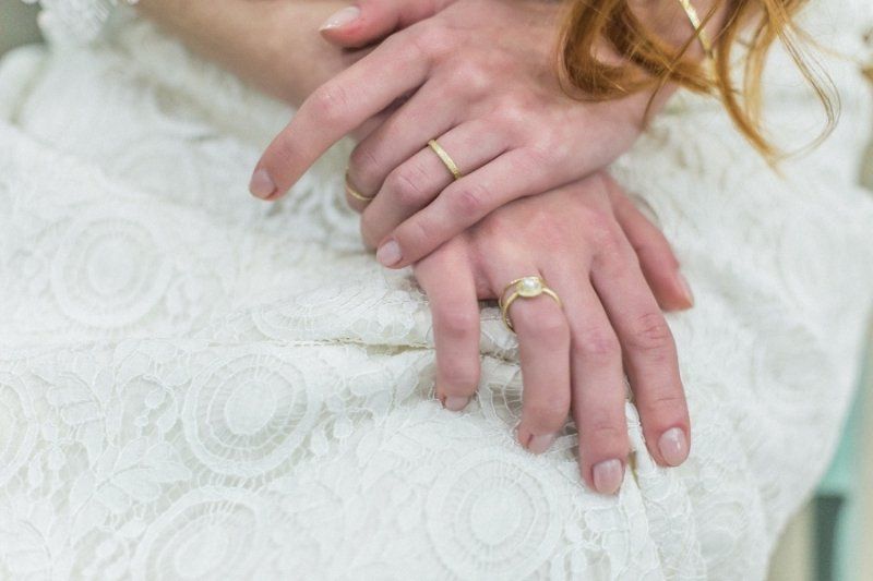 A close up of a bride and groom 's hands with wedding rings.