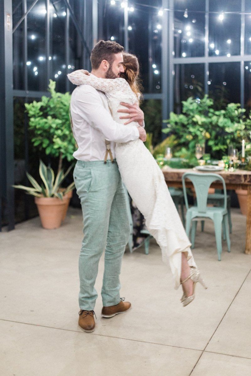 A man is holding a woman in his arms in a greenhouse.