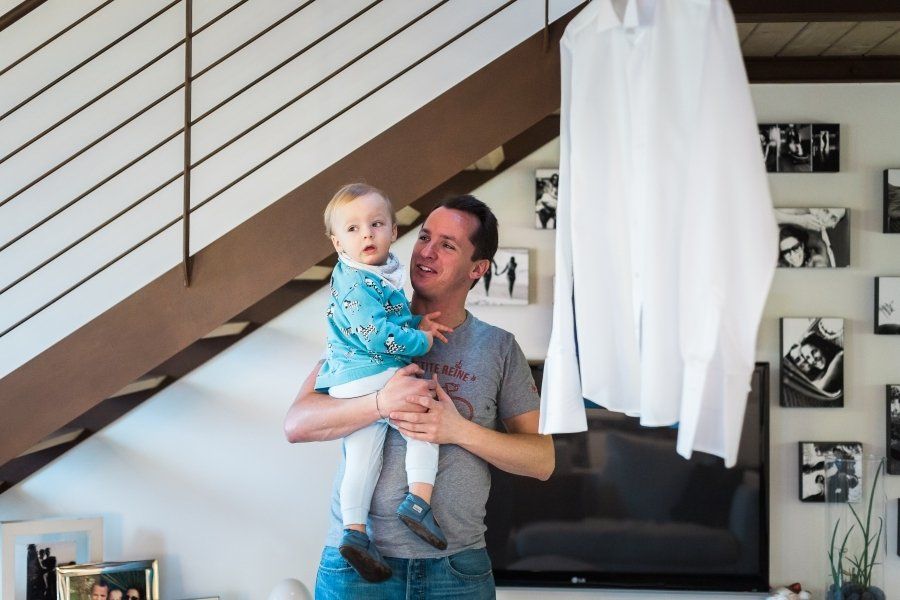 A man is holding a baby in his arms in a living room.