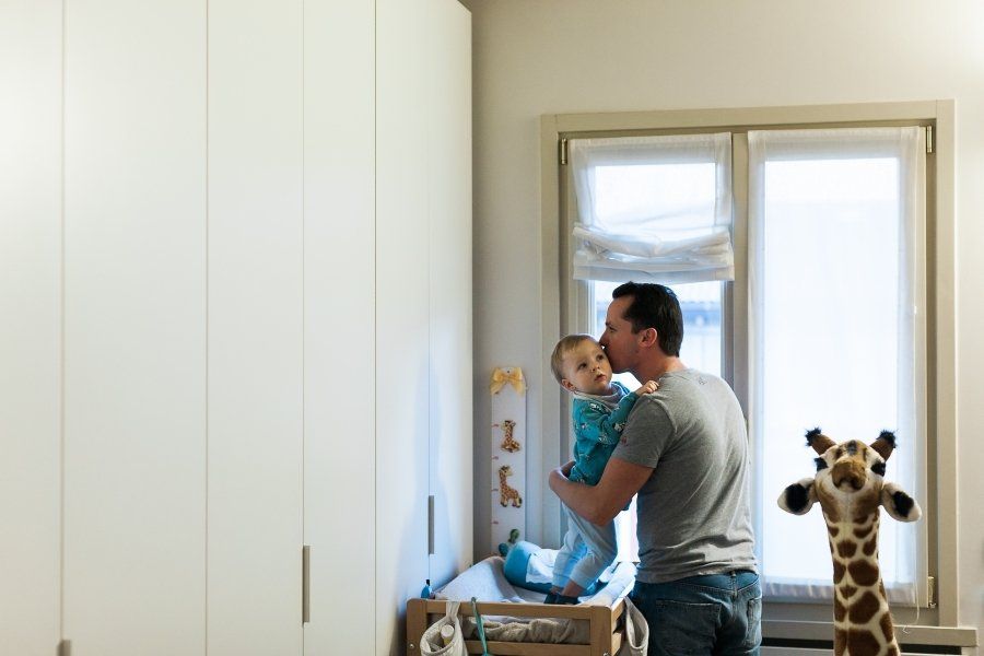 A man is holding a baby in his arms in a room.