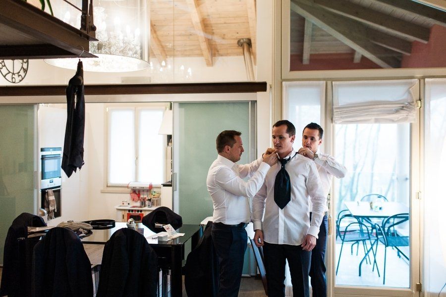 Three men are getting ready for a wedding in a living room.