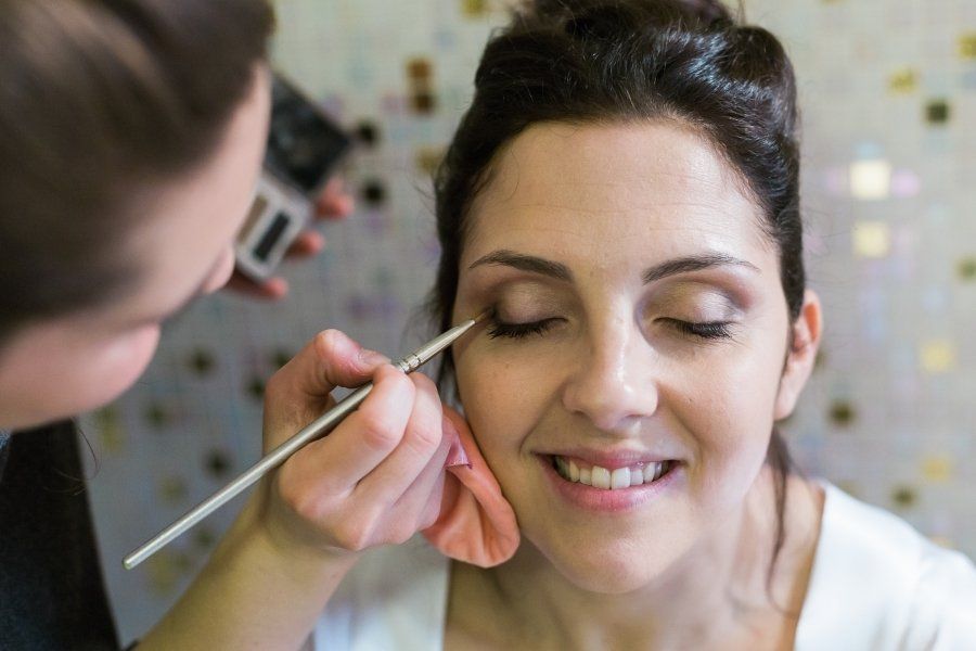 A woman is getting her makeup done by a makeup artist.