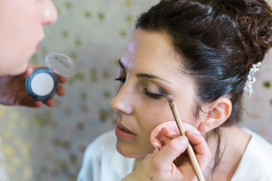 A woman is getting her makeup done by a makeup artist.