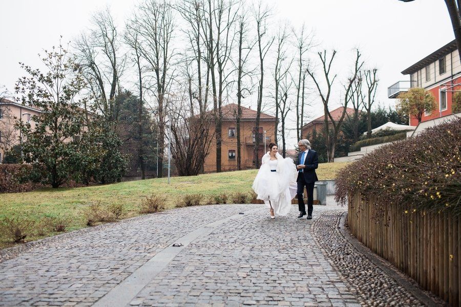 A bride and groom are walking down a cobblestone street.