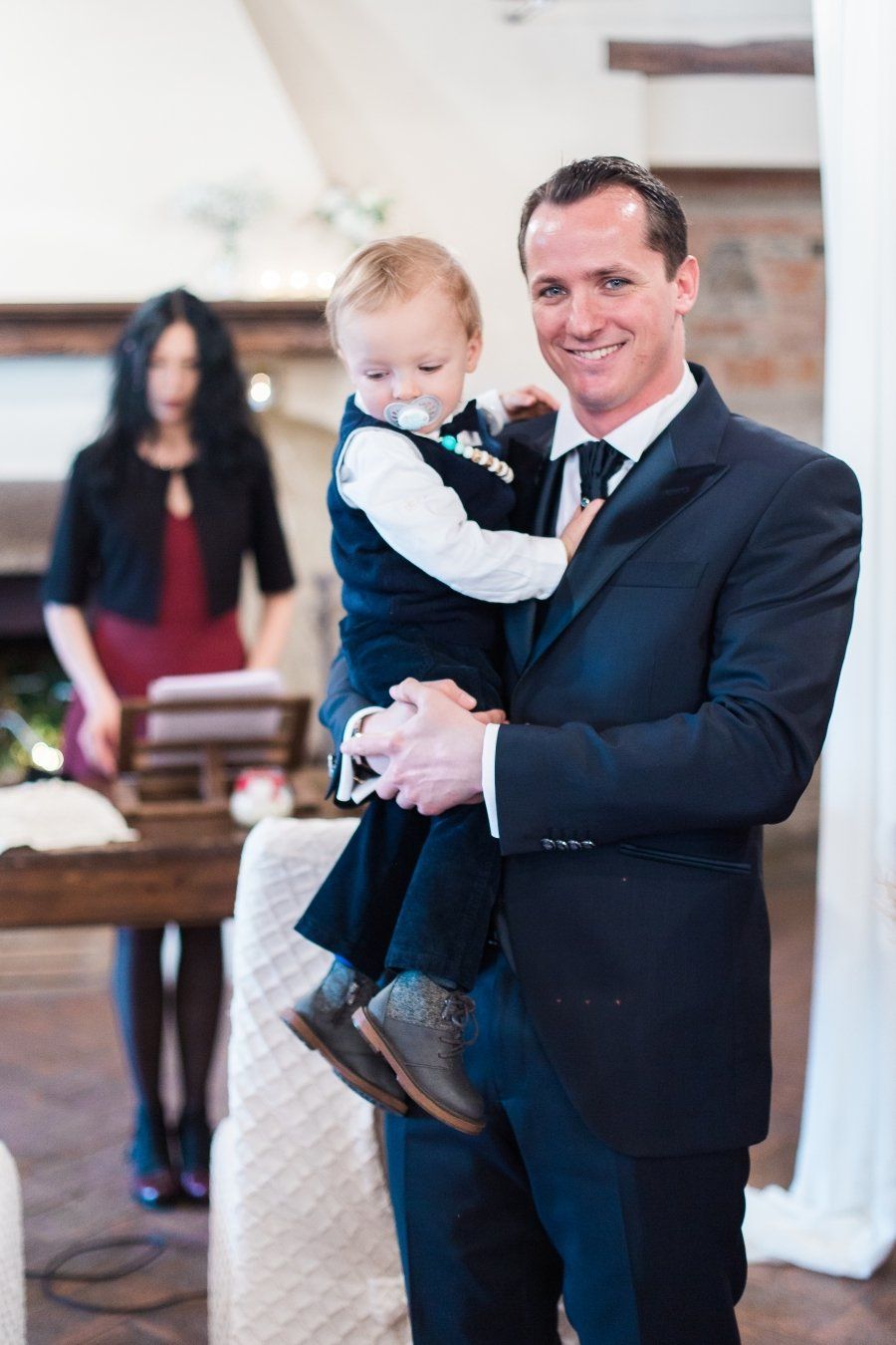 A man in a suit is holding a baby in his arms.
